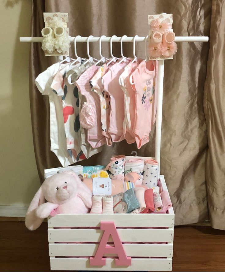 a baby's clothing rack with clothes and a teddy bear