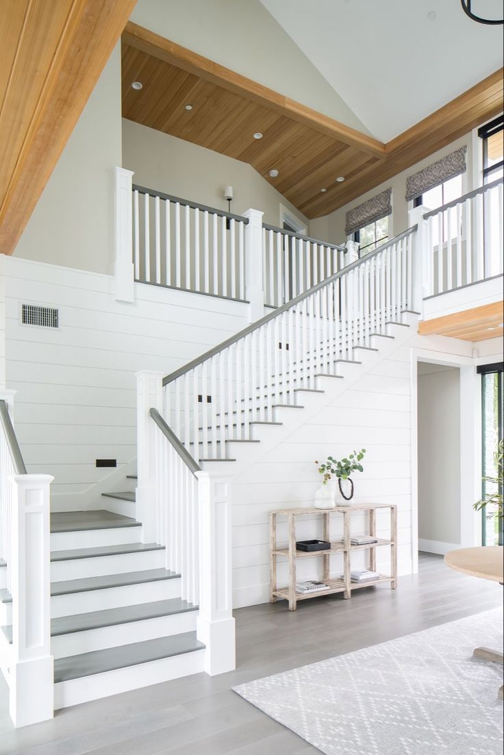 a living room filled with furniture next to a white stair case and wooden flooring