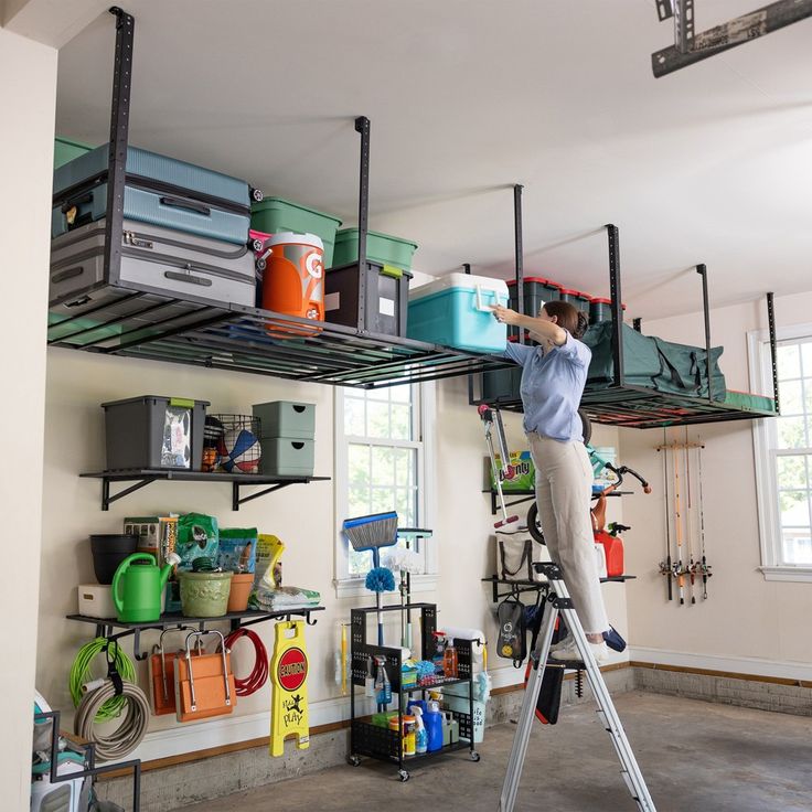 a woman is standing on a ladder and cleaning the shelves in her garage with buckets