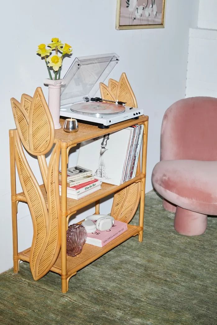 a pink chair sitting next to a table with a record player on top of it