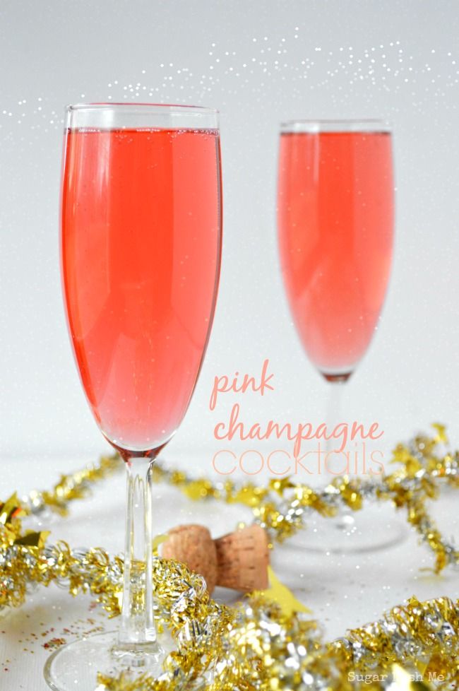 two wine glasses filled with pink champagne next to gold confetti on a table