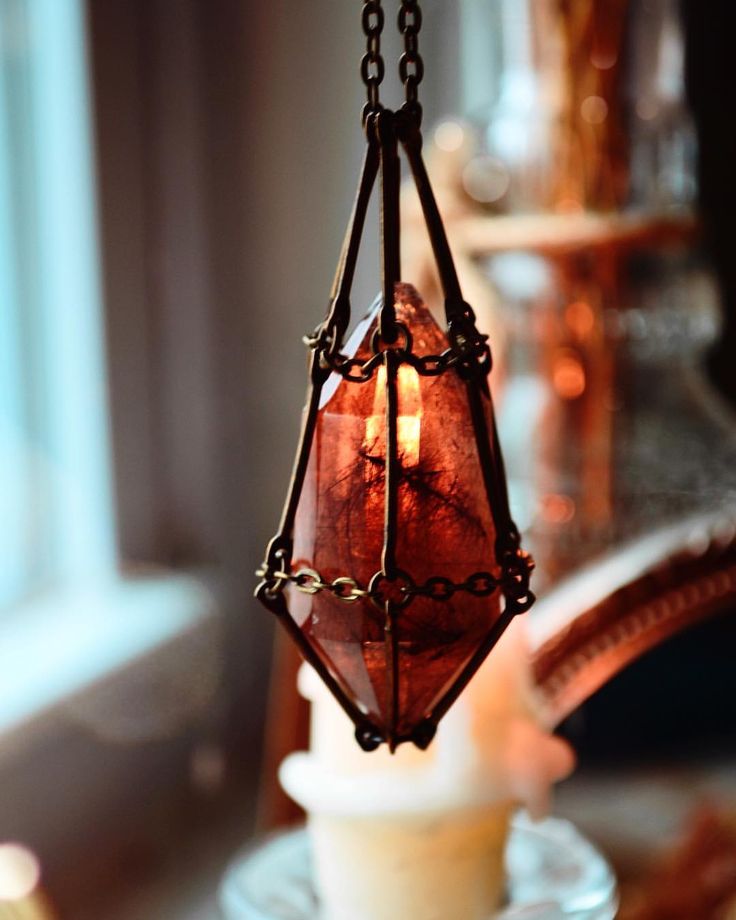 a light hanging from the ceiling in front of a window with a candle inside it