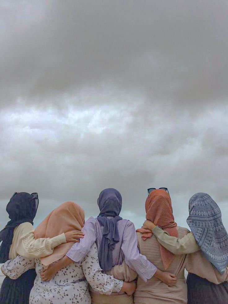 four women are sitting on a bench with their backs to the camera