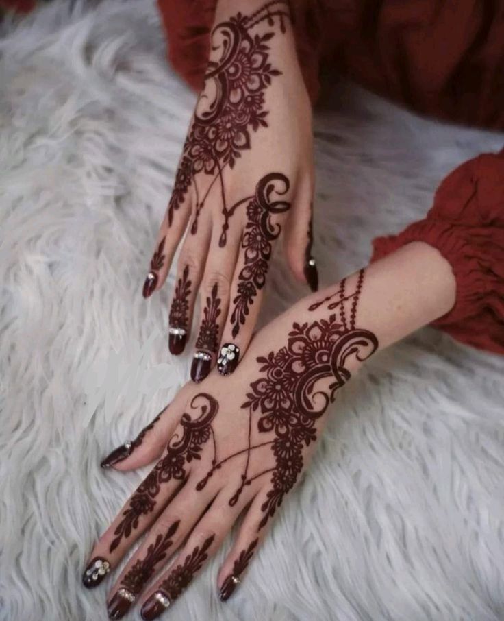 a woman's hand with henna tattoos on it and her hands painted red