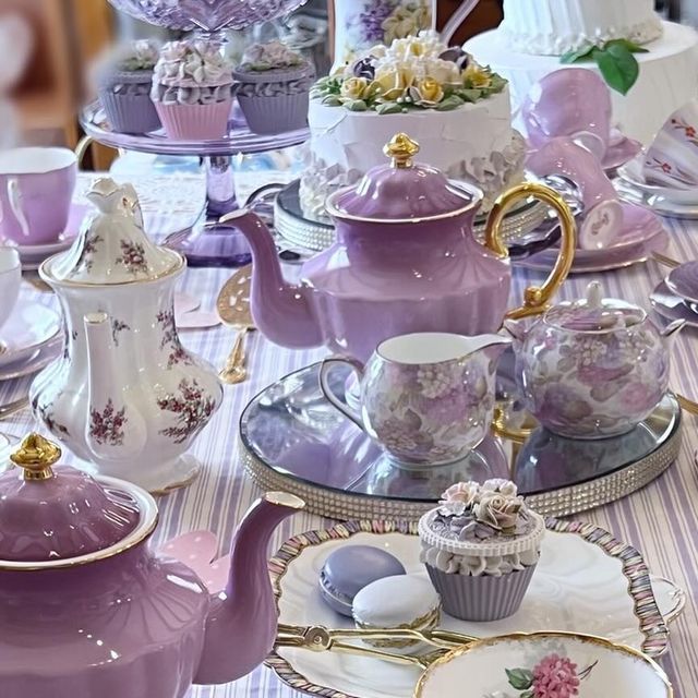 a table topped with purple and white dishes filled with tea pots, cups and saucers