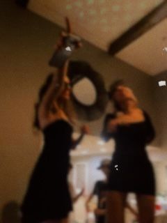 two women in black dresses are holding up an object