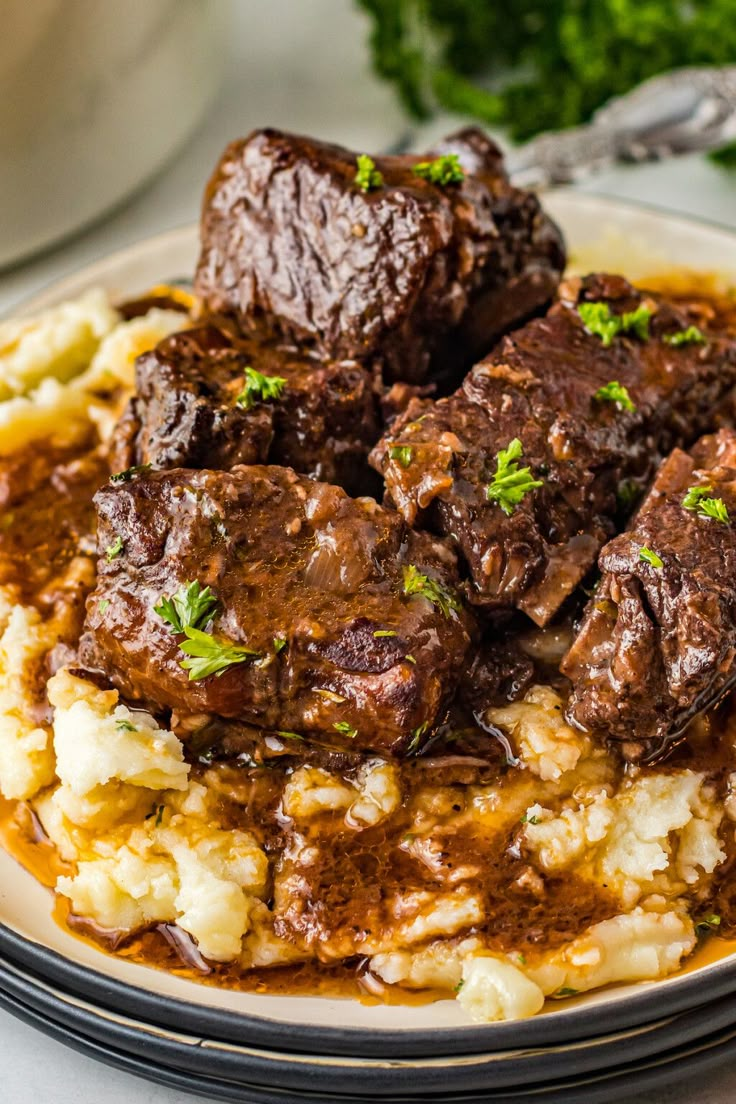 a white plate topped with meat and potatoes covered in gravy on top of a table