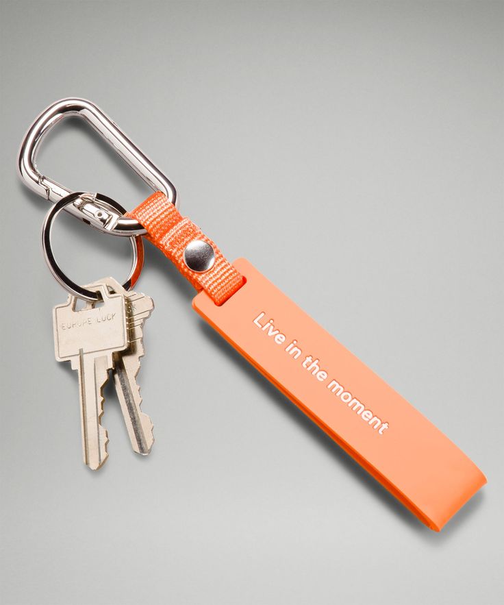 an orange keychain that says live in the moment and has two keys attached to it