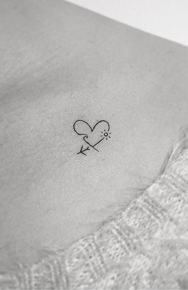 a small heart with an arrow tattoo on the side of a woman's stomach