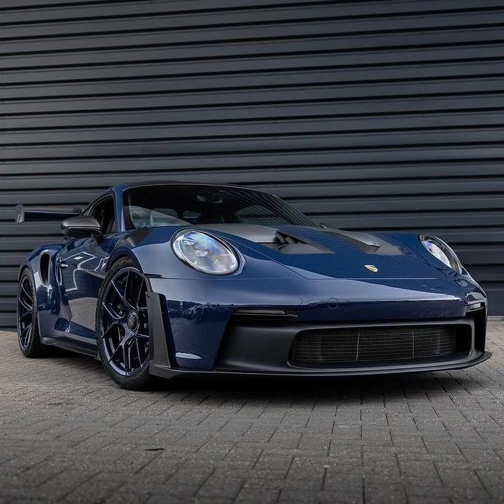 a blue sports car parked in front of a garage door next to a black wall