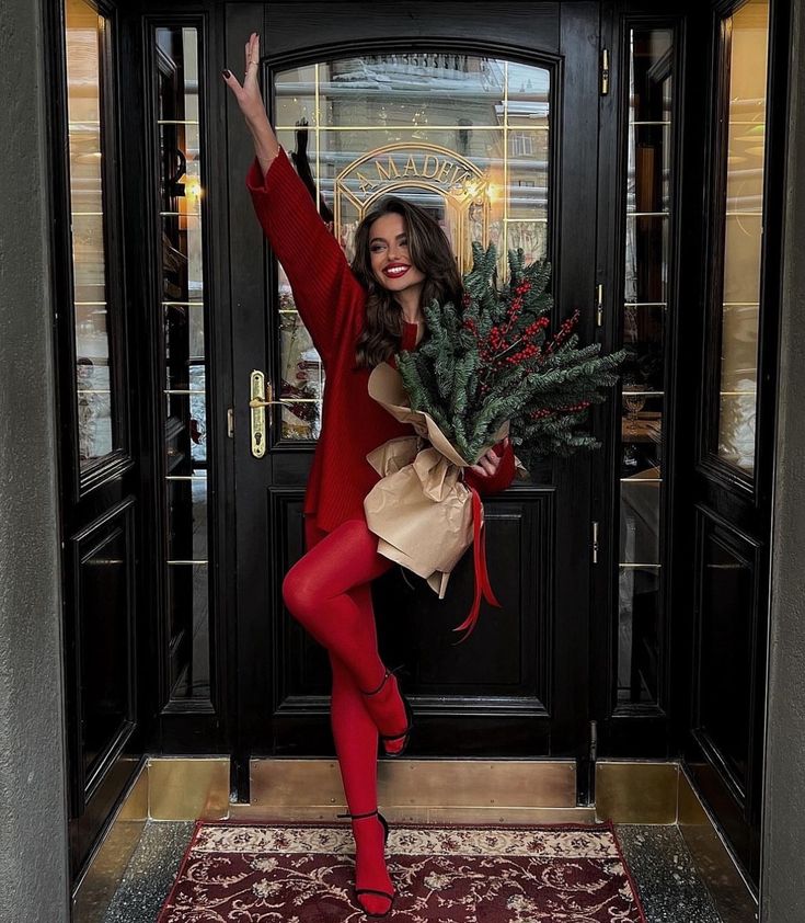 a woman in tights and stockings holding a christmas tree on the front steps of a building