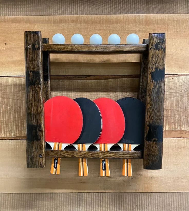 four ping pong paddles in a wooden rack