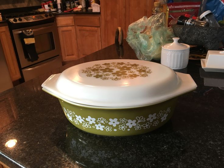 a green and white casserole dish sitting on top of a counter next to an oven