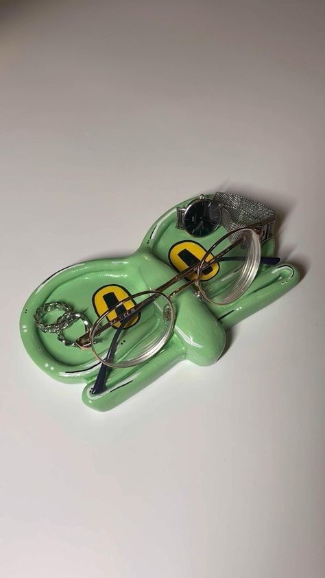 a pair of glasses sitting on top of a green frog keychain