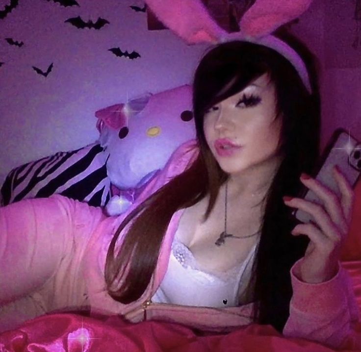 a woman laying in bed wearing bunny ears and holding a cell phone