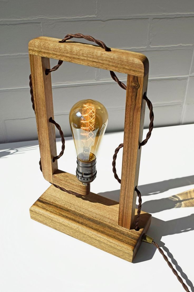 a light bulb sitting inside of a wooden frame on top of a white tablecloth