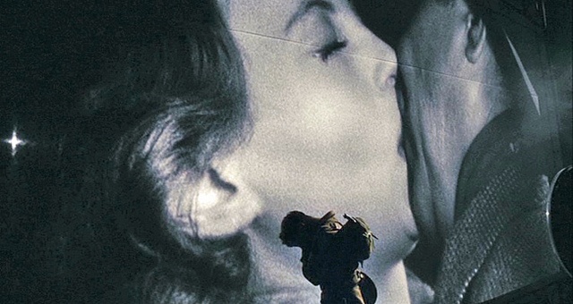 a man and woman kissing in front of a movie poster