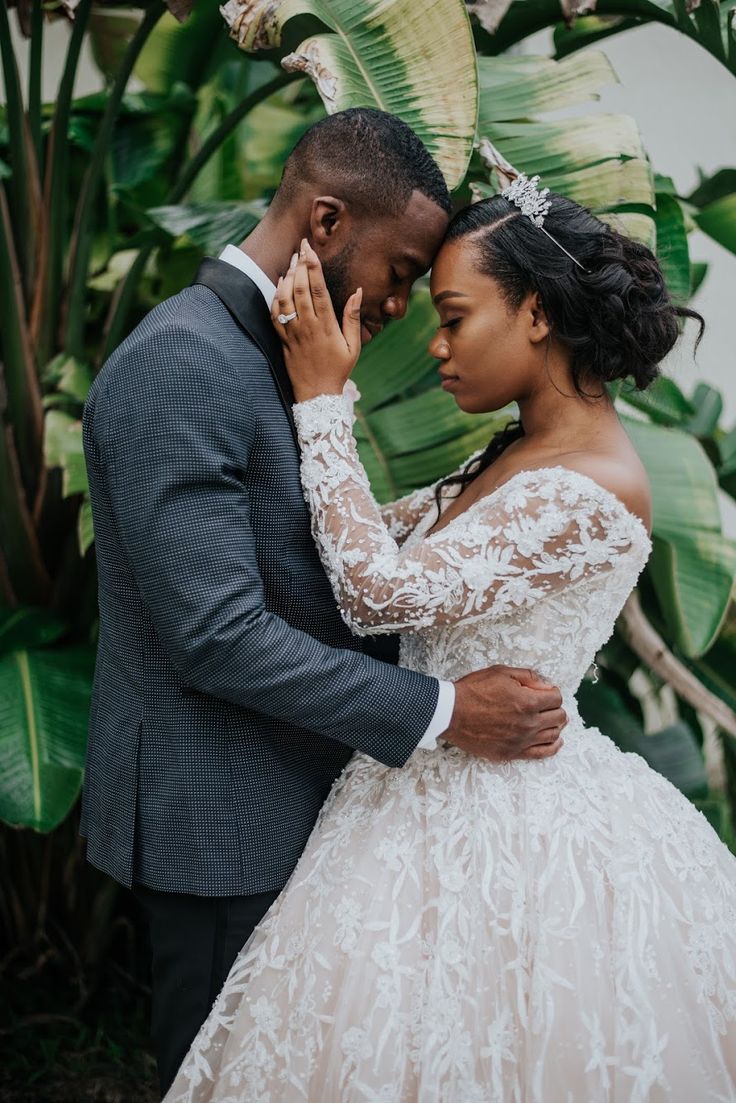 a bride and groom embracing each other in front of some tropical plants at their wedding