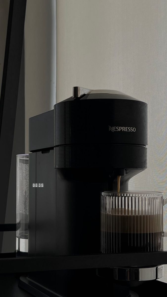 an espresso machine sitting on top of a black shelf next to a window