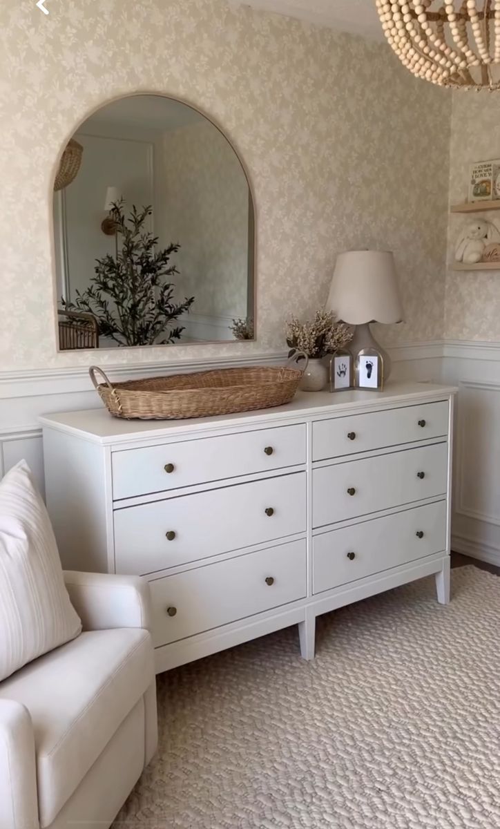 a white dresser and chair in a room with a chandelier hanging from the ceiling