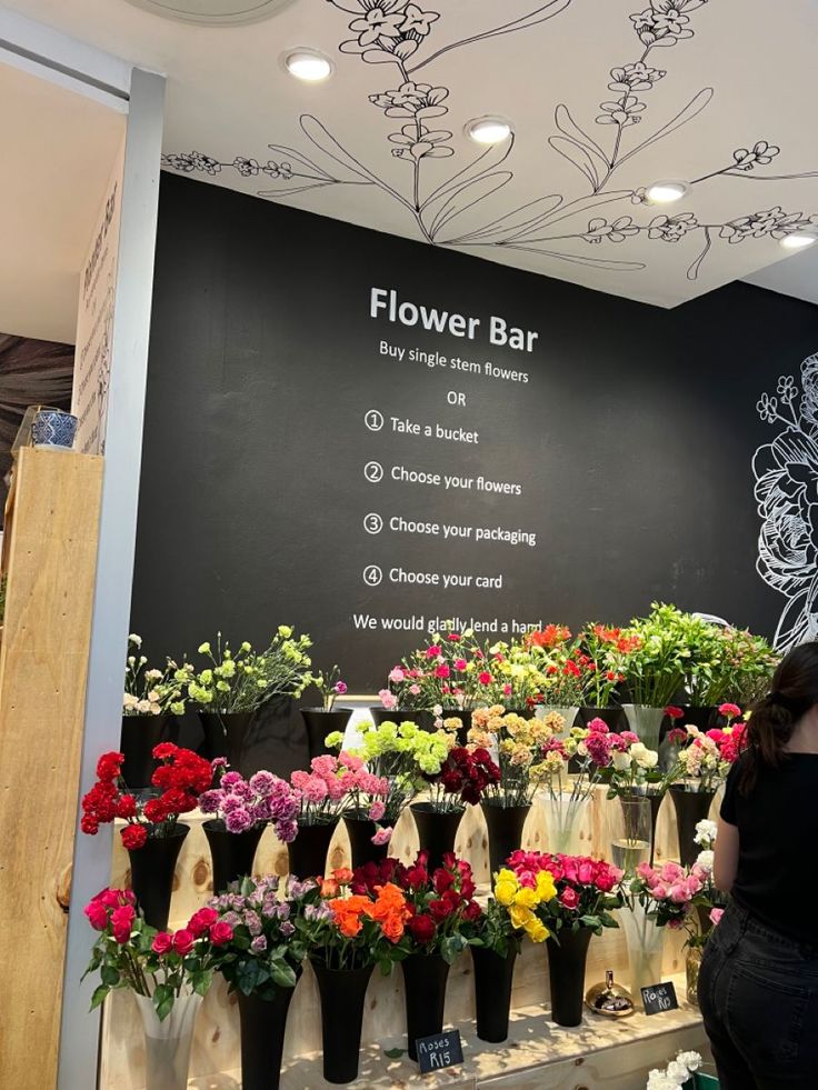 a woman standing in front of a flower bar