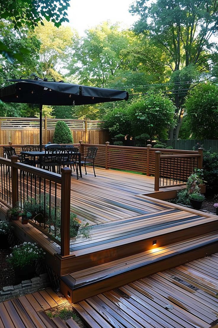 a wooden deck with an umbrella over it and lights on the side, surrounded by greenery