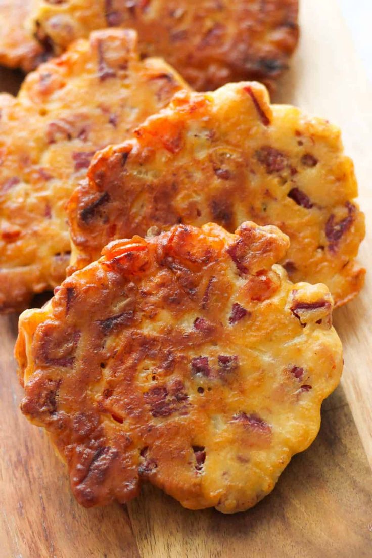 three cheesy potato cakes on a wooden cutting board, ready to be eaten