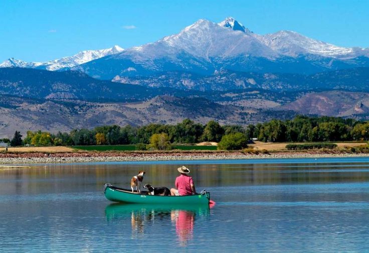 a man and his dog in a canoe on the water with mountains in the background