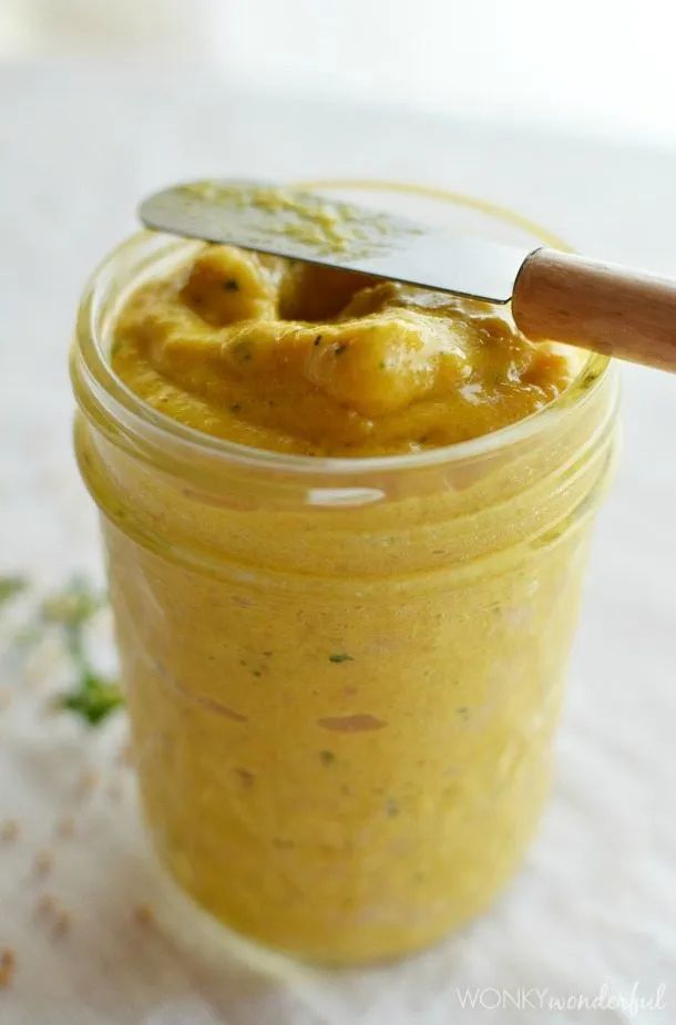 a jar filled with yellow food and a wooden spoon