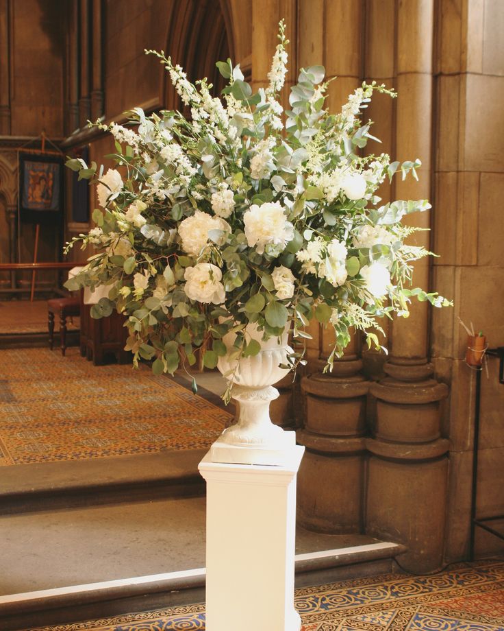 a vase filled with white flowers sitting on top of a floor next to a doorway