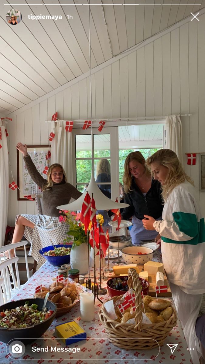 people standing around a table with food on it and flags hanging from the ceiling above them