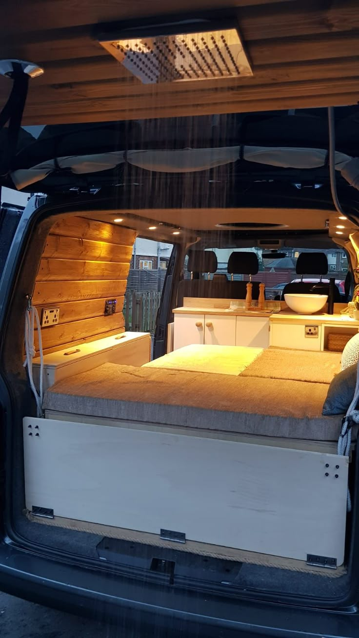 the back end of a van with an open hatchback door and bed in it