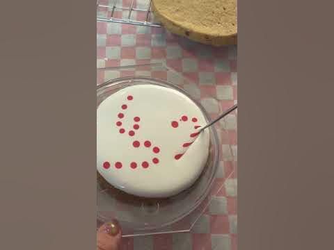 a white cake with red dots on it sitting on top of a plastic tray next to a piece of bread