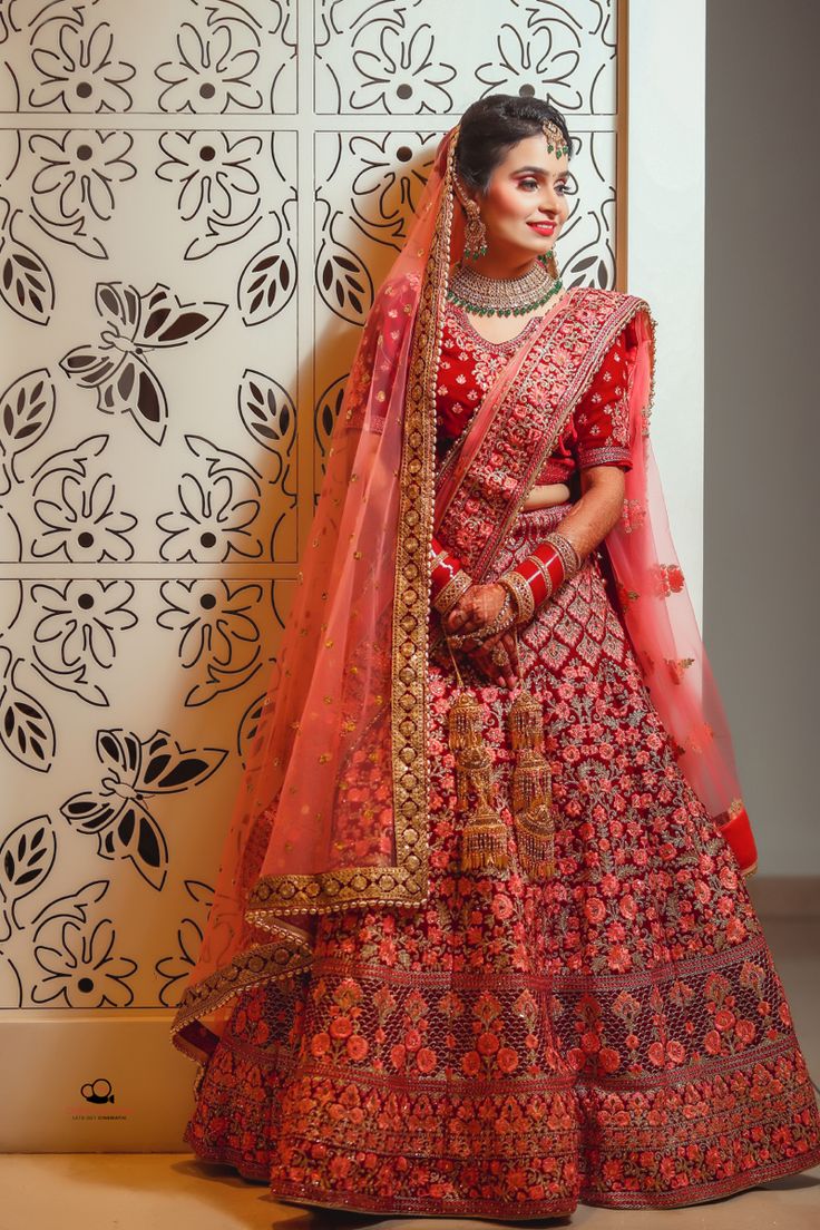 a woman in a red lehenga standing next to a wall