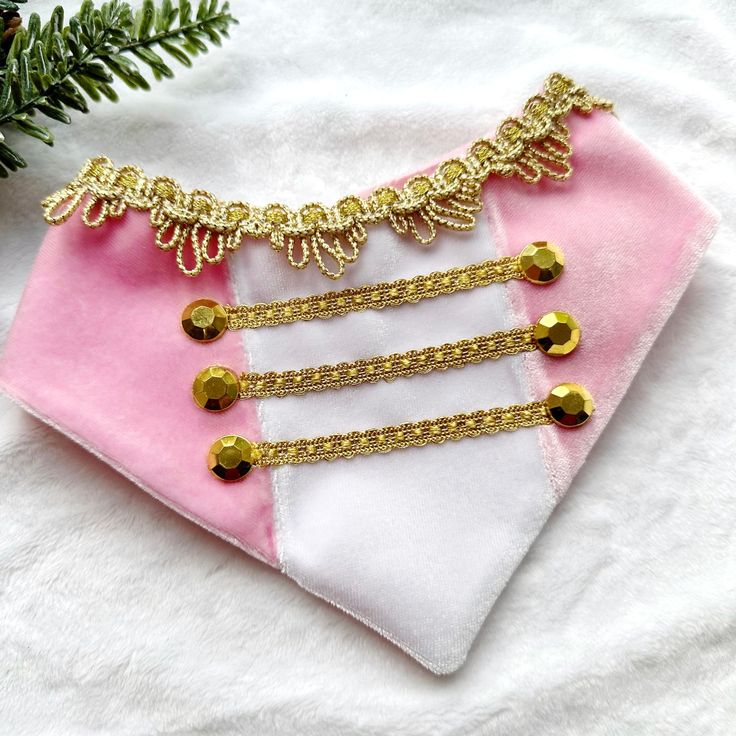 a pink and white christmas ornament with gold trimmings on top of it