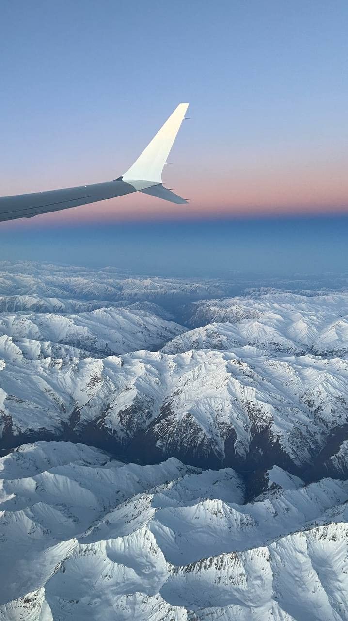 an airplane wing flying over snow covered mountains