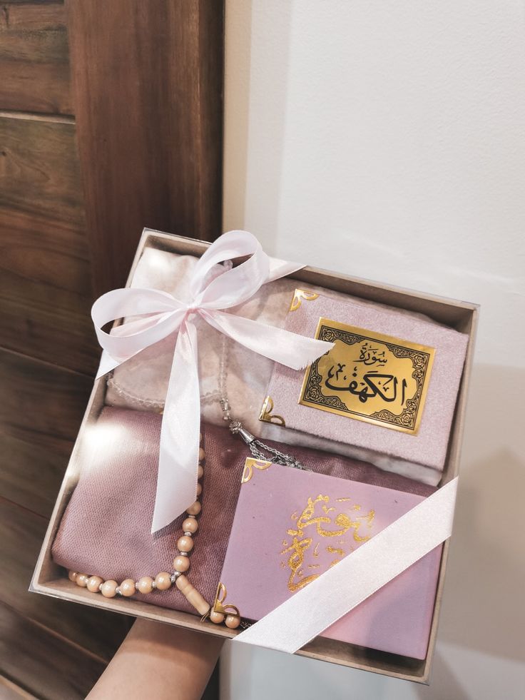 a person holding an open box with some items in it and a white ribbon on the top