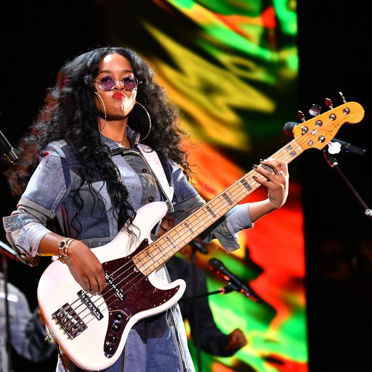 a woman holding a bass guitar on stage