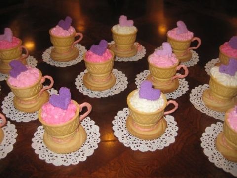 there are many cups that have pink and purple frosting in them on the table