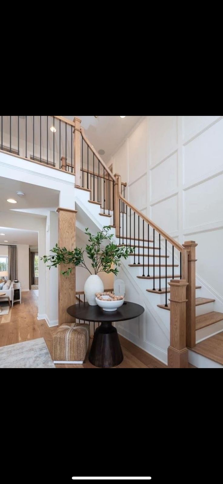 a living room filled with furniture and a stair case in front of a white wall