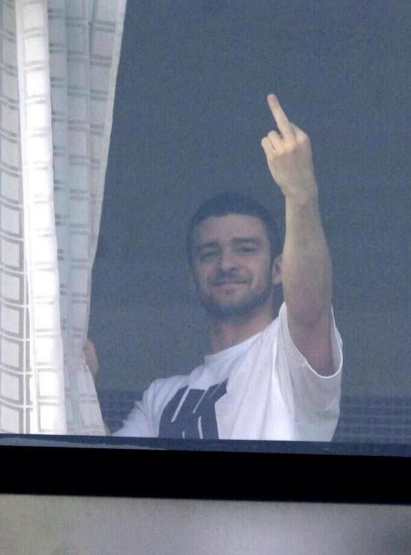 a man standing in front of a window making the peace sign