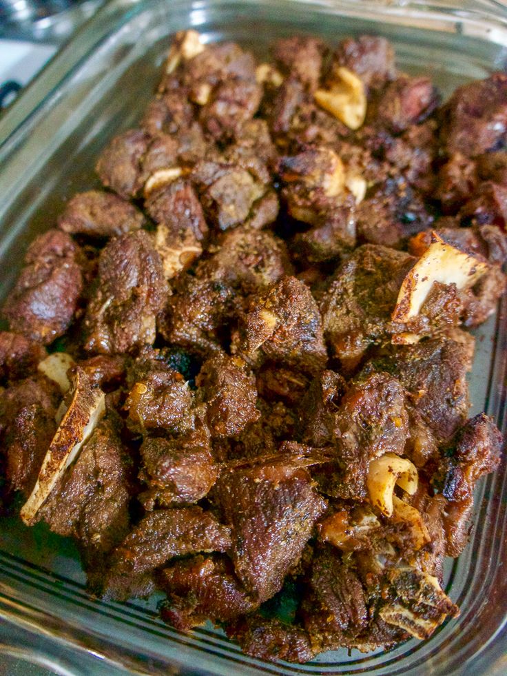 a glass dish filled with meat and other food items on top of a stovetop