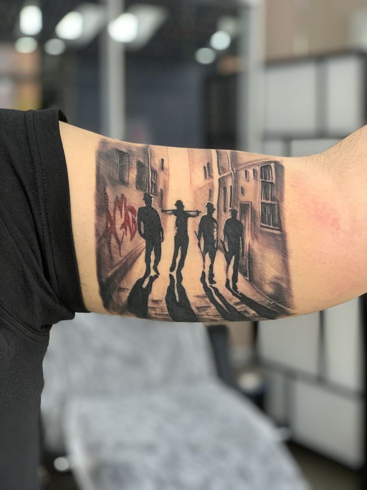 a man with a tattoo on his arm that has two people walking down the street