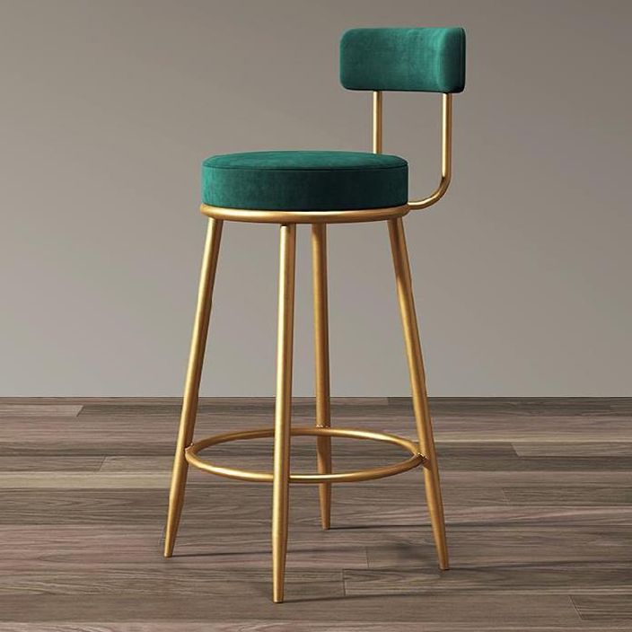 an upholstered bar stool with a green velvet seat and backrest, on a wood floor