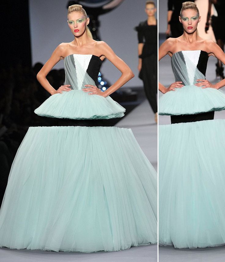 a model walks down the runway wearing a blue and white gown with black accents on it