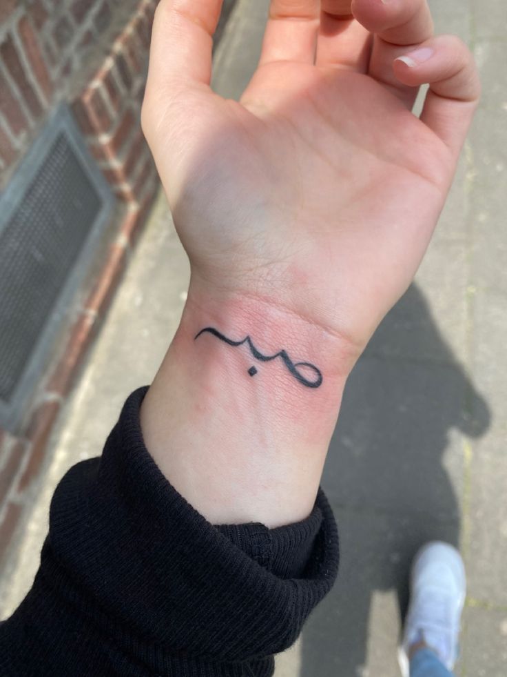 a hand with a small tattoo on it