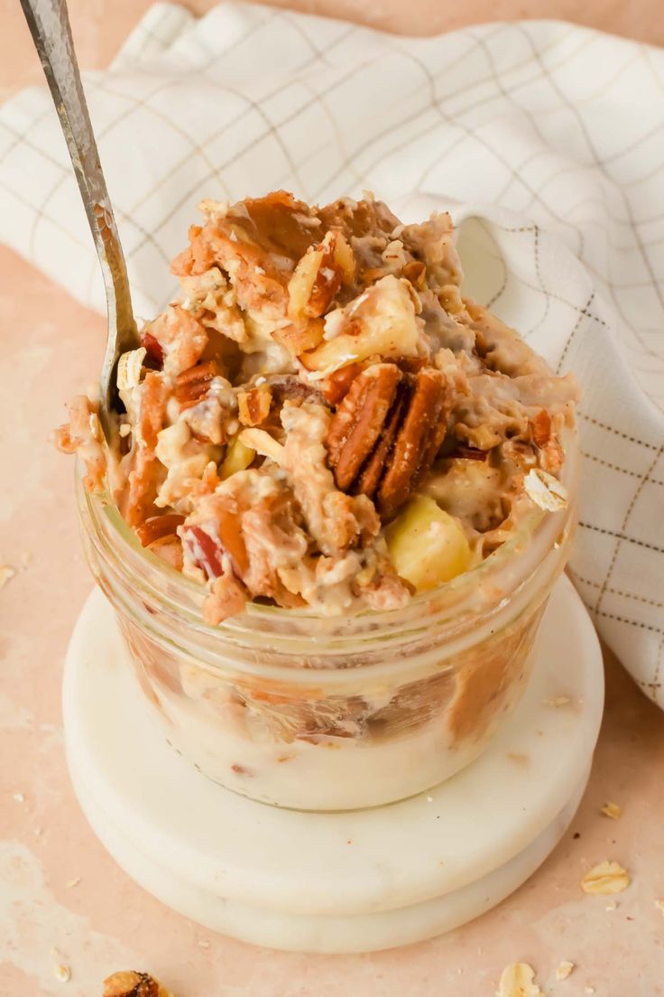 a glass jar filled with food sitting on top of a white plate next to a spoon