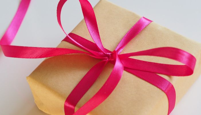 a wrapped present box with pink ribbon on it