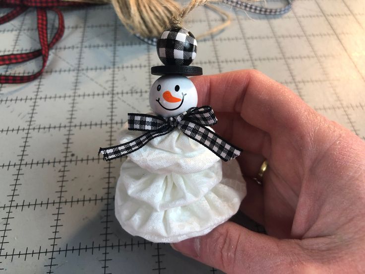 a snowman ornament being held by someone's hand