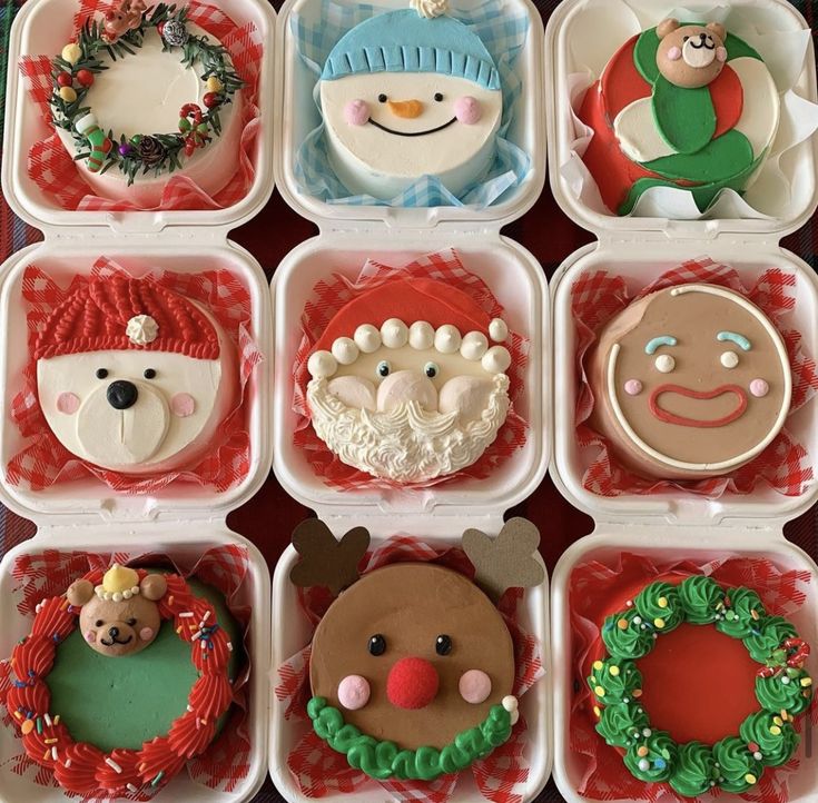 there are many decorated cupcakes in the box on the table with christmas decorations